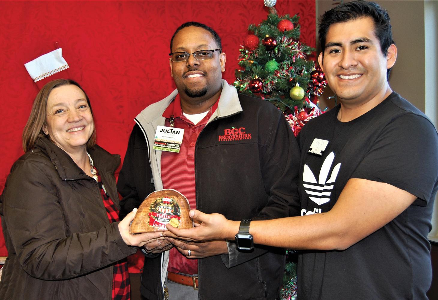 Denise Butler, executive director of North Ellis County Outreach is presented with one of hundreds of Hormel Hams donated by Brookshire Grocery Company and Hormel Foods. Shown with Butler is JulianHoward, Red Oak Brookshires store manager and Brec Evans-Orrell, NECO client assistance director.