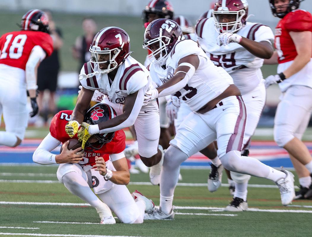 Linebacker Torrall Stocker Jr. (7) and defensive end Kaleb Ross (23) meet at the Mustang’s quarterback for one of the Hawk’s six sacks in the game. Photo by Steve Patterson / Moving Pictures.
