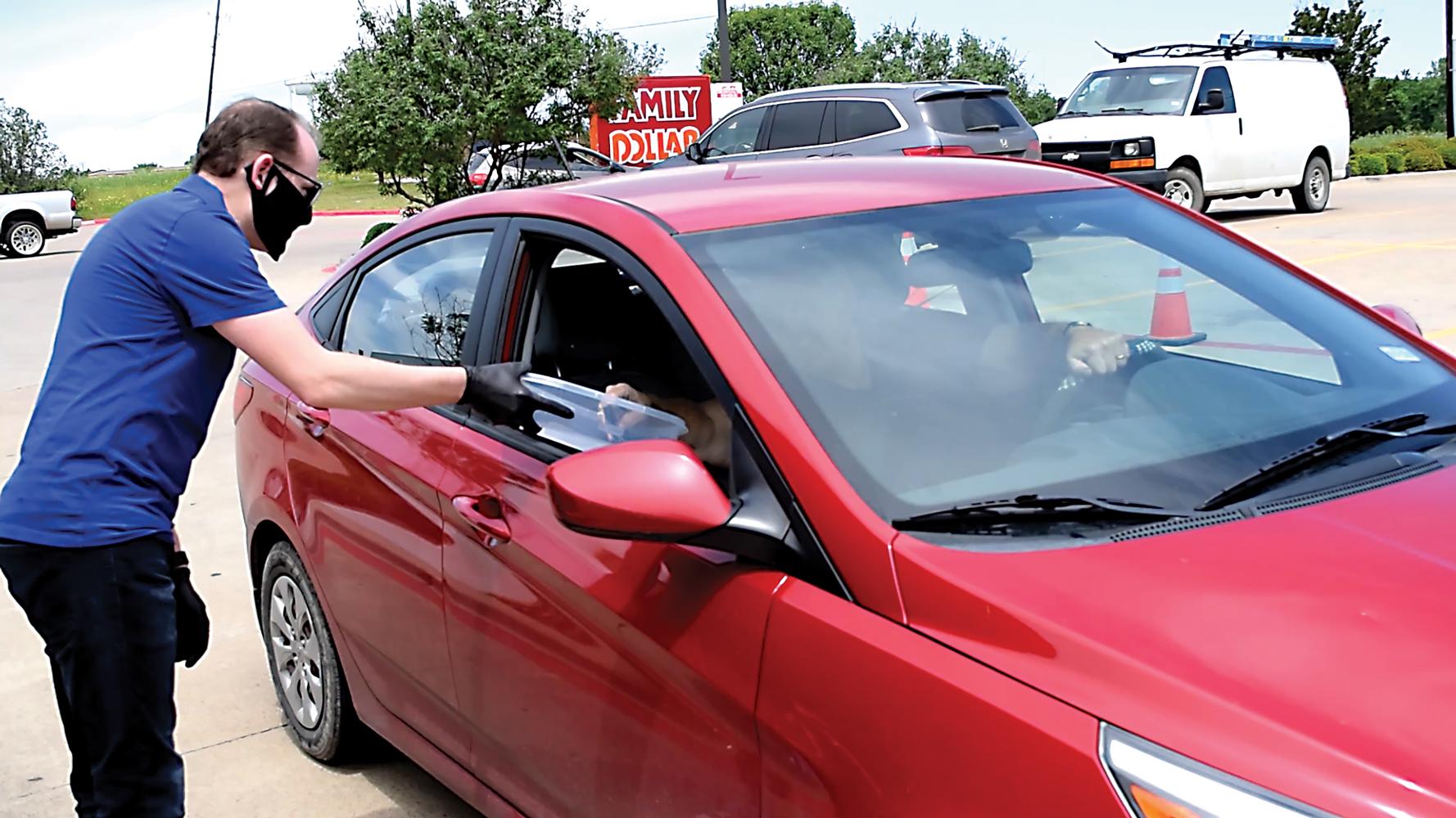 Covenant Church Pastor Michael Masek is shown passing out one of the 1,200 masks the church purchased for give away Saturday. Photo by Charles D. Hatfield Jr. / The Ellis County Press.