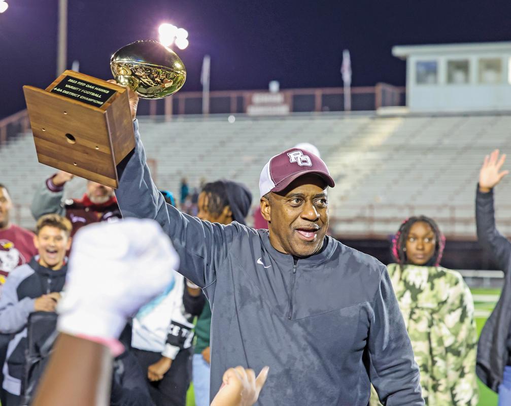Hawks Head Football Coach Melvin Robinson holds up the District 4-5A I Championship trophy after the Hawks 21-7 win over Midlothian.