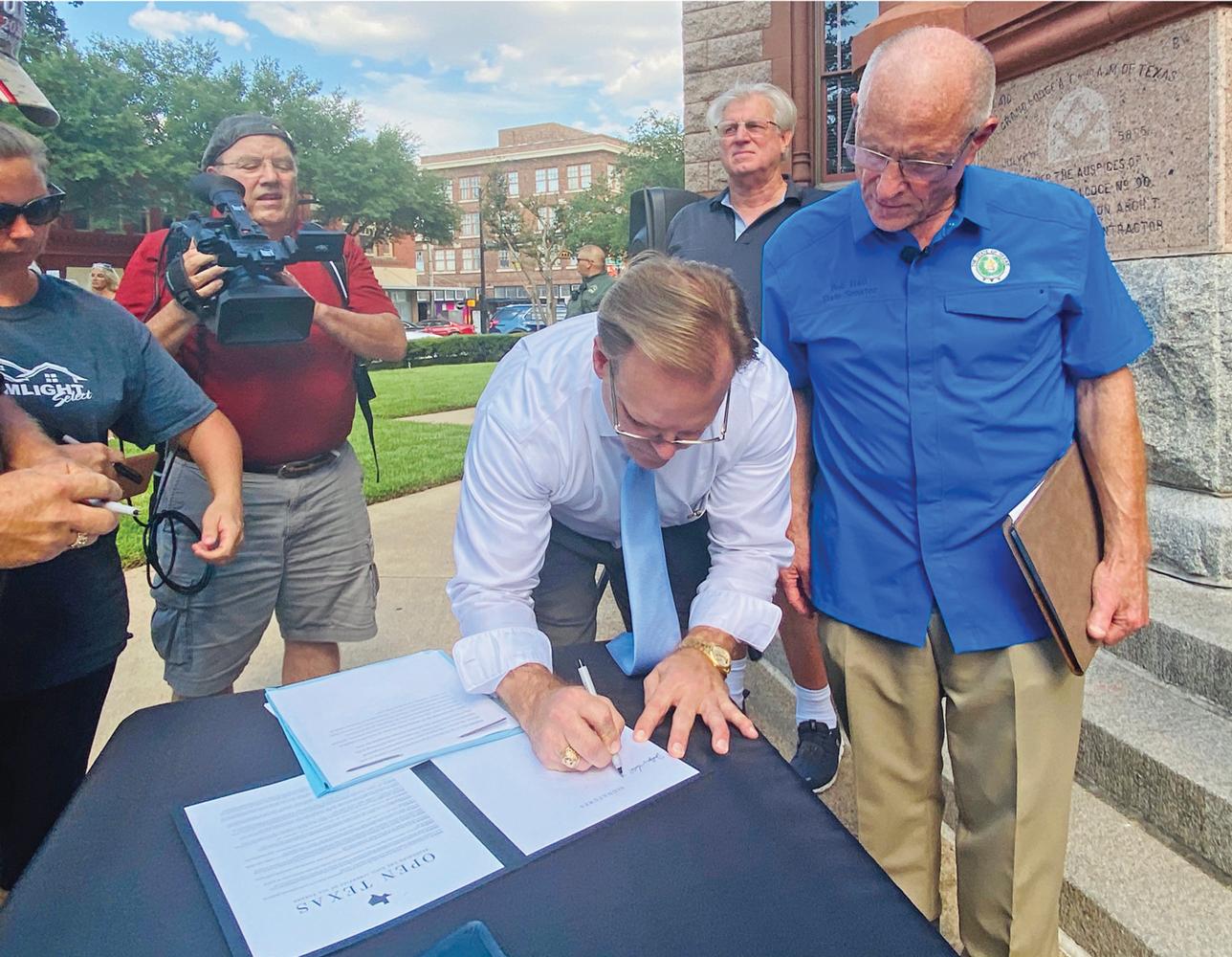 Ellis County Judge Todd Little signs the proclamation declaring “Open Texas” in front of the Ellis County Courthouse.