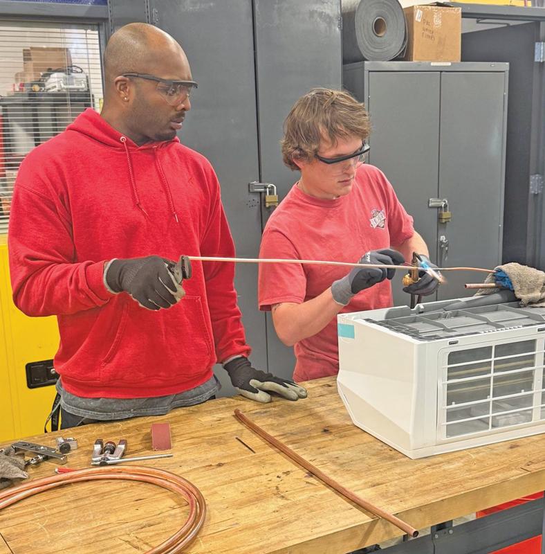 Elijahwah McCowan (left) and Edward Wilds (right, from Palmer), two HVAC Technology students at TSTC’s North Texas campus, repair a mini-split system for the campus’s IT room.