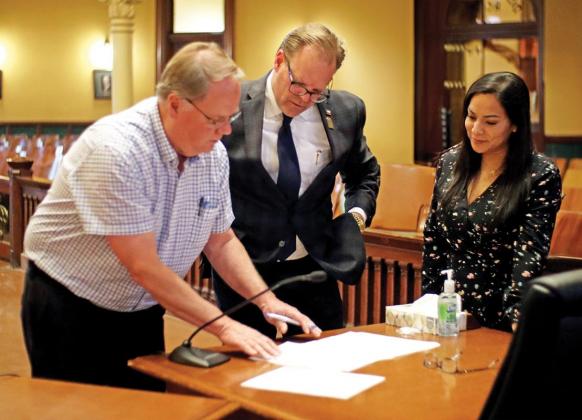 Louis Ponder signs the oath of office for Commissioner Precinct 4 under the watchful eyes of County Judge Todd Little and County Clerk Krystal Valdez.
