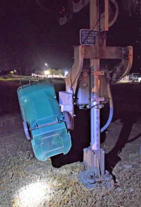 Trash container impaled on railroad crossing arm.
